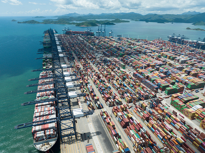 Aerial view of a container port with rows of shipping containers and docked cargo ships