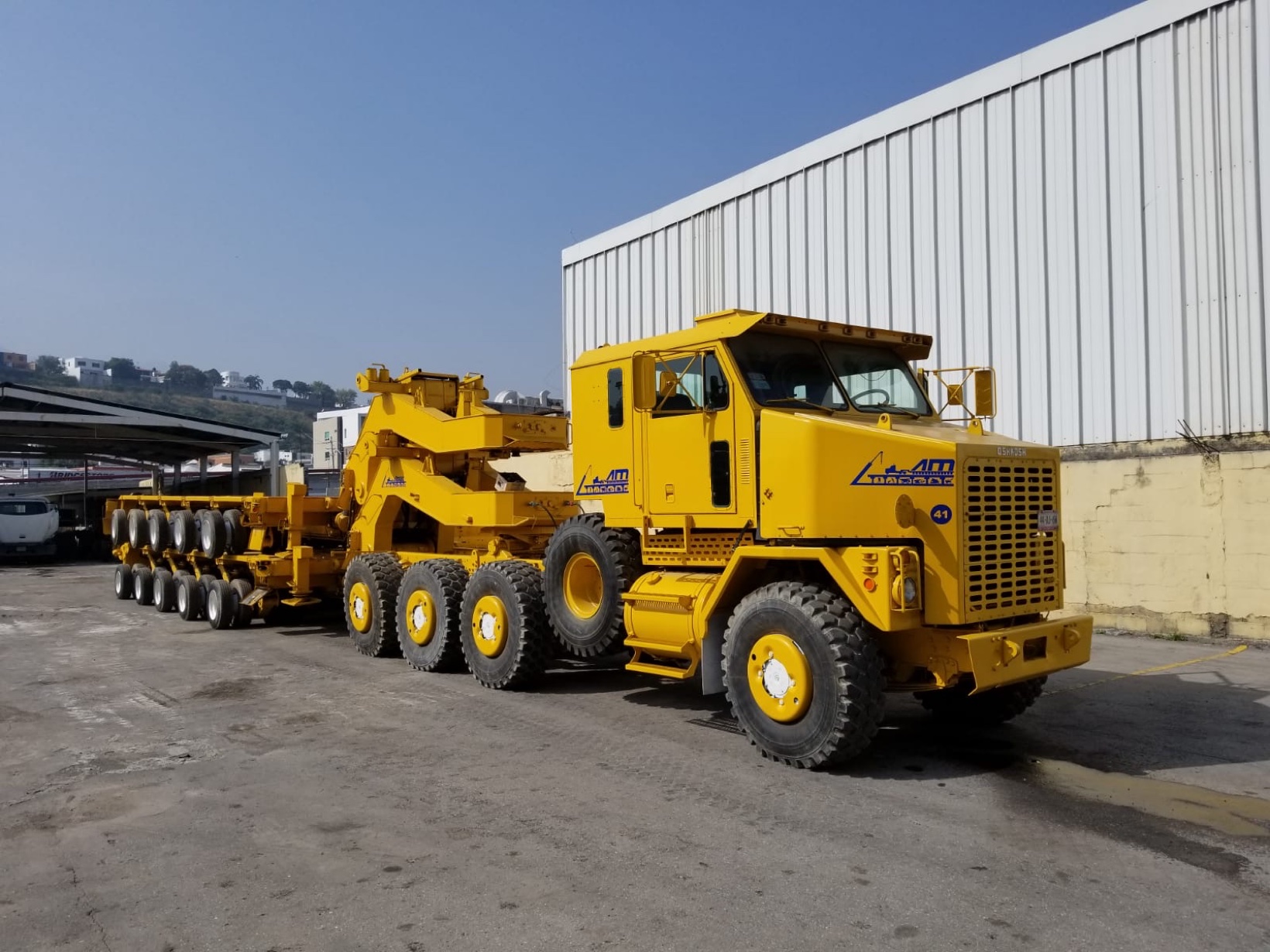 Yellow Oshkosh heavy-haul tractor with a multi-axle lowboy trailer