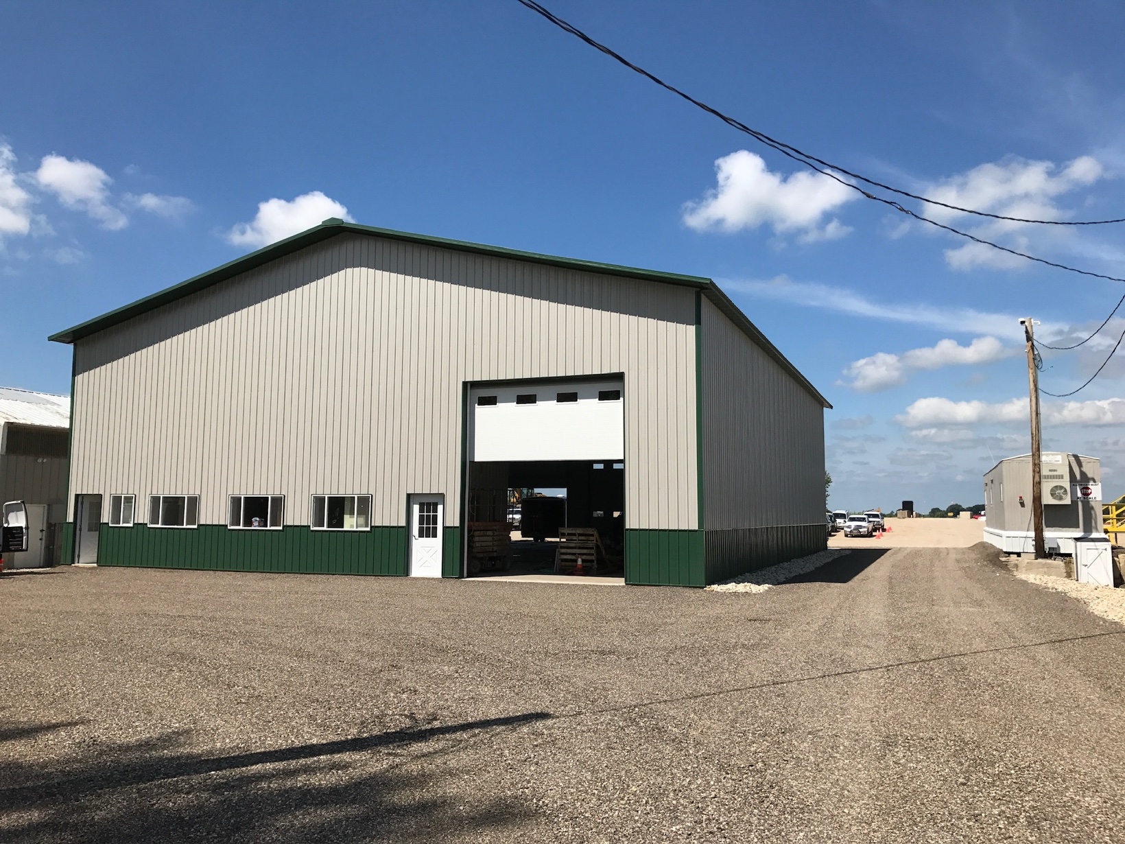 Large metal warehouse building with an open bay door under a blue sky