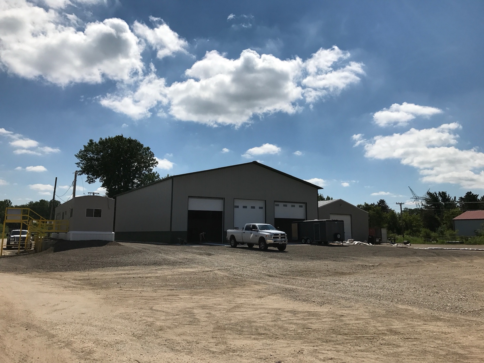 Warehouse building with three bays and a white pickup truck parked in front