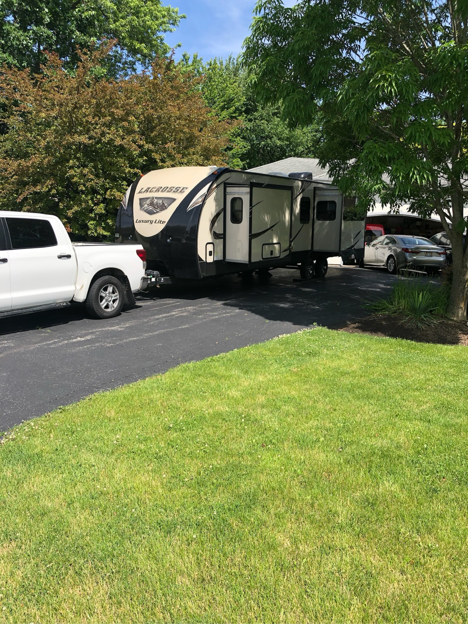 White pickup truck and Lacrosse travel trailer parked in a residential driveway