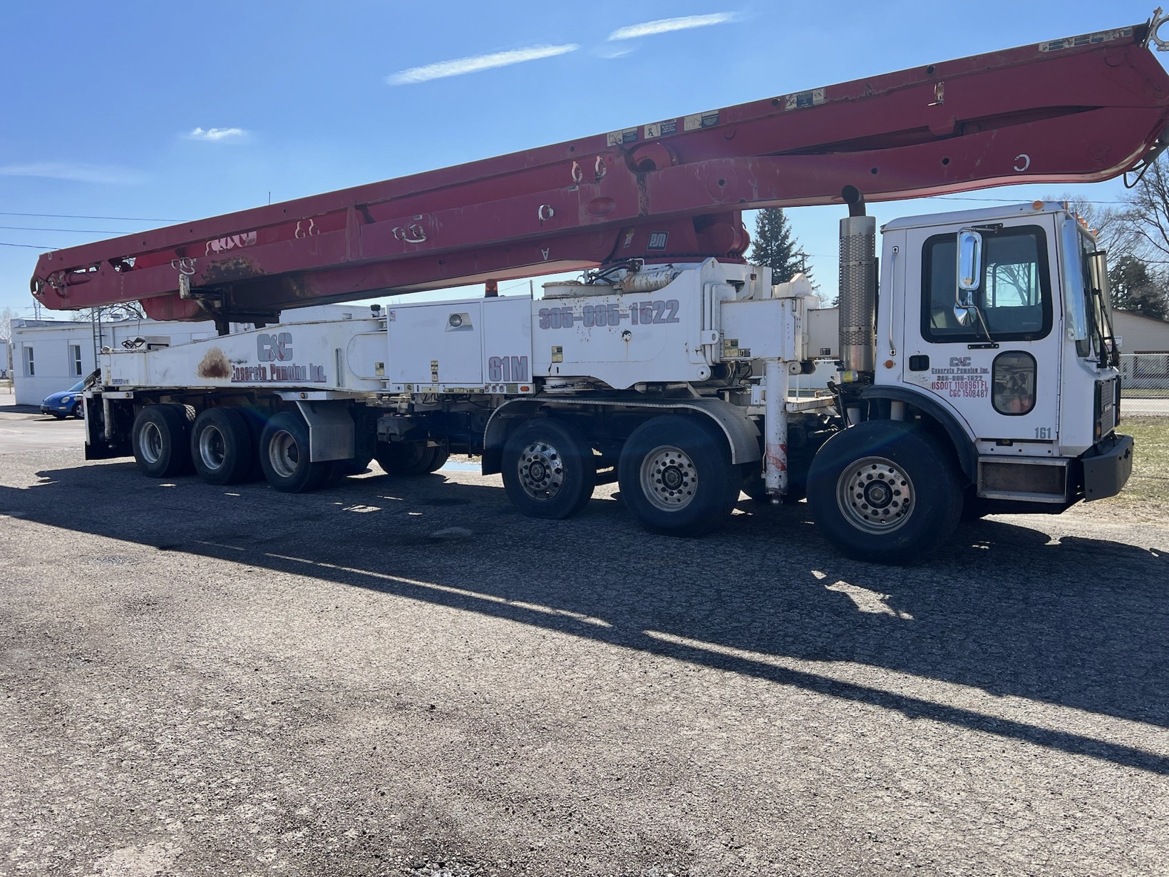 White truck-mounted concrete pump with a long red boom